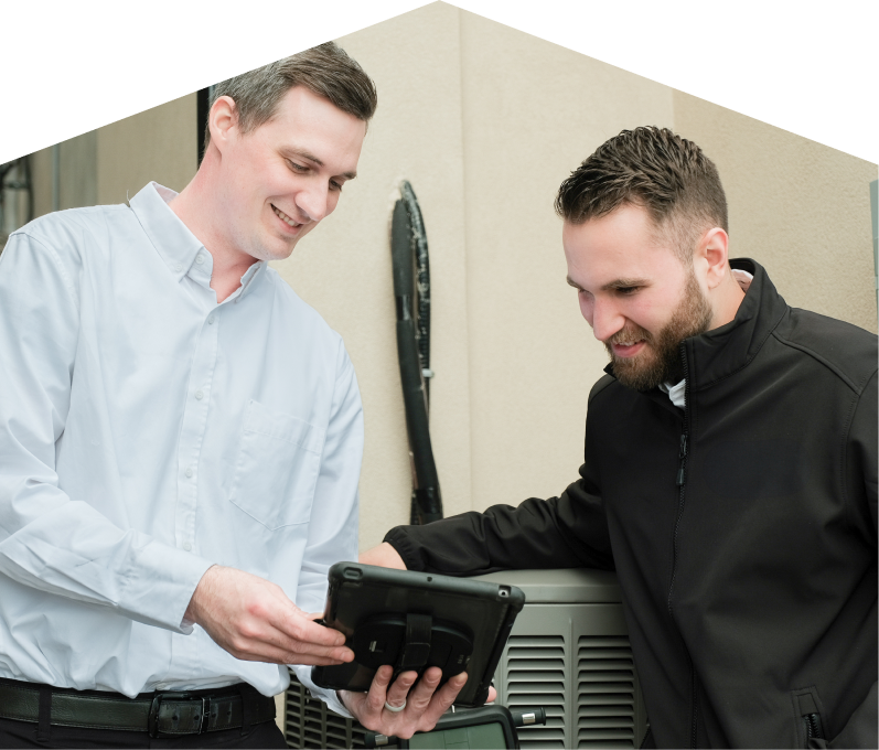 A Home Aire Care technician in a white shirt shows service details on a tablet to a smiling client in a black jacket, standing beside an AC unit outside a beige building. A Home Aire Care technician in a white shirt shows service details on a tablet to a smiling client in a black jacket, standing beside an AC unit outside a beige building.