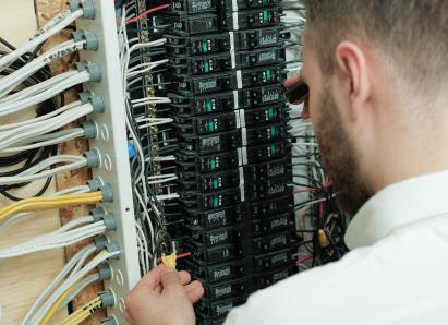 Home Aire Care electrical technician examining wiring connections inside a circuit breaker panel for a residential service check. Home Aire Care electrical technician examining wiring connections inside a circuit breaker panel for a residential service check.