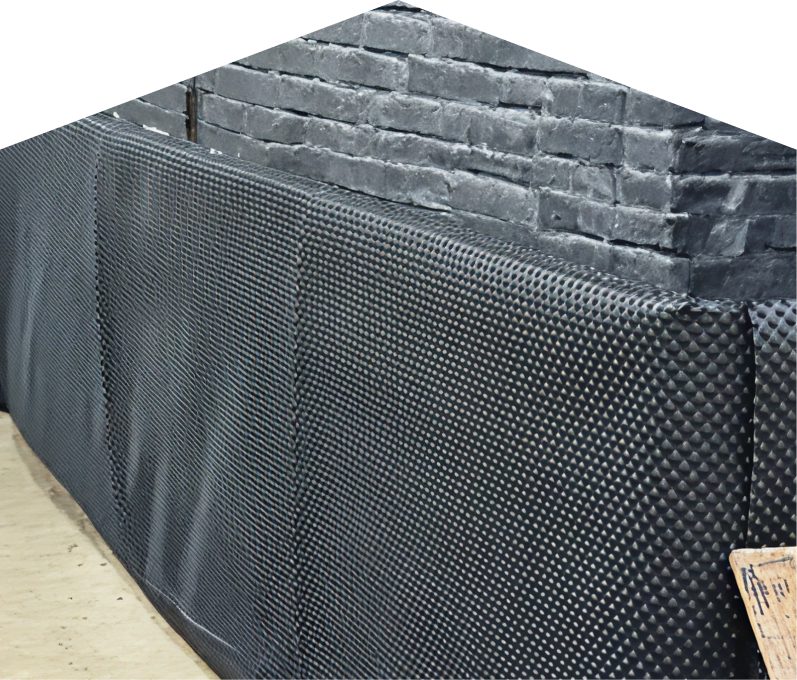 Exterior basement waterproofing completed by Home Aire Care, showing a sealed foundation wall with dimpled waterproof membrane partially installed on a brick surface, preventing moisture infiltration. Exterior basement waterproofing completed by Home Aire Care, showing a sealed foundation wall with dimpled waterproof membrane partially installed on a brick surface, preventing moisture infiltration.