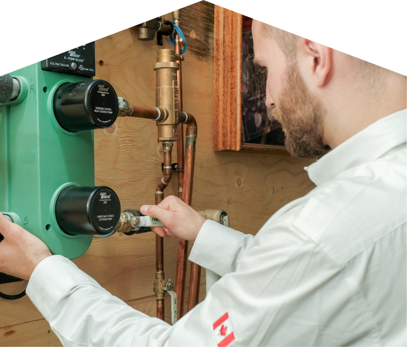 Home Aire Care HVAC specialist performing boiler installation, securing a valve on a new hydronic heating system with copper piping and a green circulation pump mounted on a wooden wall. Home Aire Care HVAC specialist performing boiler installation, securing a valve on a new hydronic heating system with copper piping and a green circulation pump mounted on a wooden wall.