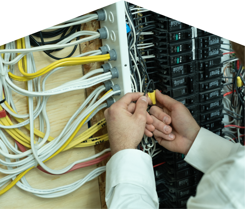 Home Aire Care service personnel working on electrical installations, connecting wires inside a residential breaker panel with neatly arranged colored cables on a plywood backing. Home Aire Care service personnel working on electrical installations, connecting wires inside a residential breaker panel with neatly arranged colored cables on a plywood backing.