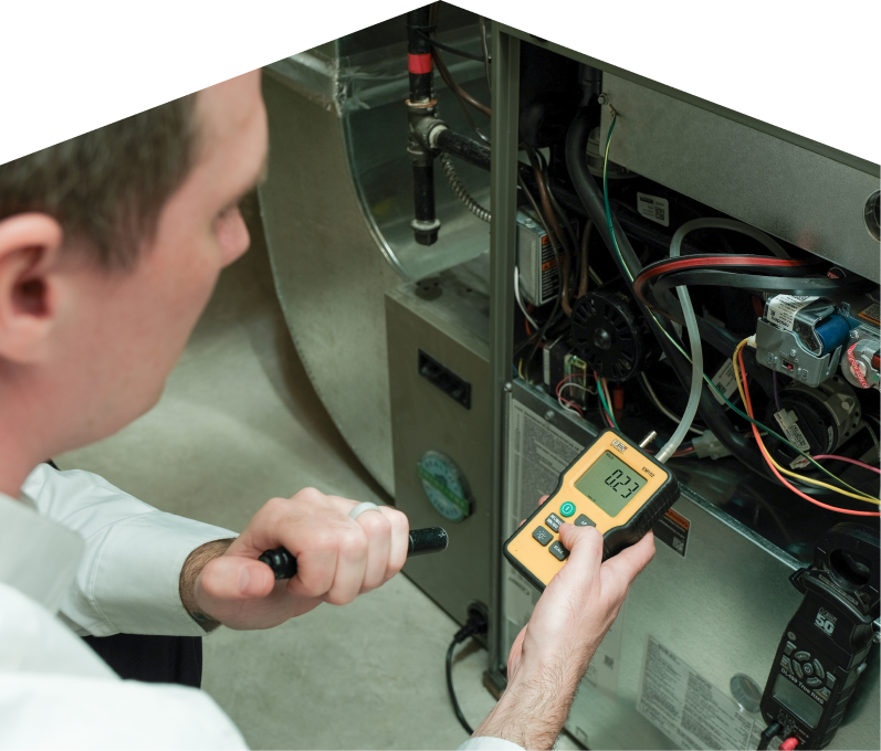Home Aire Care HVAC specialist performing furnace repair on a heating system, using a digital manometer to check pressure. Home Aire Care HVAC specialist performing furnace repair on a heating sy