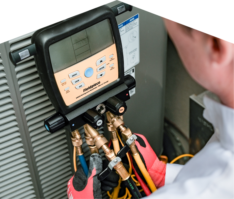 A Home Aire Care home service crew member uses a digital manifold gauge to check refrigerant levels on an HVAC unit for service. A Home Aire Care home service crew member uses a digital manifold gauge to check refrigerant levels on an HVAC unit for service.
