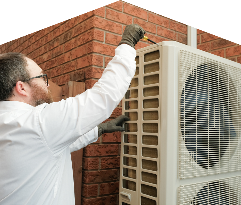 Home Aire Care HVAC specialist using a screwdriver to complete a heat pump installation beside a brick wall. Home Aire Care HVAC specialist using a screwdriver to complete a heat pump installation beside a brick wall.