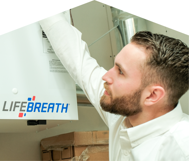 Home Aire Care indoor air quality specialist inspects a Lifebreath ventilation unit related to UV air purifiers, with ductwork and boxes in the background. Home Aire Care indoor air quality specialist inspects a Lifebreath ventilation unit related to UV air purifiers, with ductwork and boxes in the background.