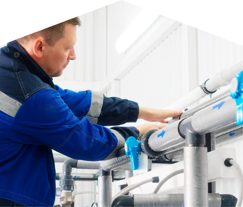 Home Aire Care water damage and restoration specialist in a blue uniform adjusts insulated piping on a water system inside a bright utility room. Home Aire Care water damage and restoration specialist in a blue uniform adjusts insulated piping on a water system inside a bright utility room.