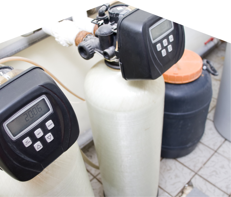 Home Aire Care water softener installation showing dual resin tanks with digital control heads and a brine tank in a tiled utility area. Home Aire Care water softener installation showing dual resin tanks with digital control heads and a brine tank in a tiled utility area.
