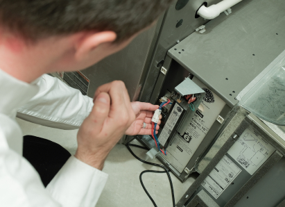 A Home Aire Care heating technician inspecting internal wiring during a service check on a residential heating unit. A Home Aire Care heating technician inspecting internal wiring during a service check on a residential heating unit.