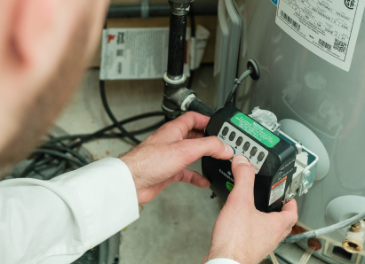 A Home Aire Care technician adjusts the control module on a residential water heater, verifying proper operating settings. A Home Aire Care technician adjusts the control module on a residential water heater, verifying proper operating settings.