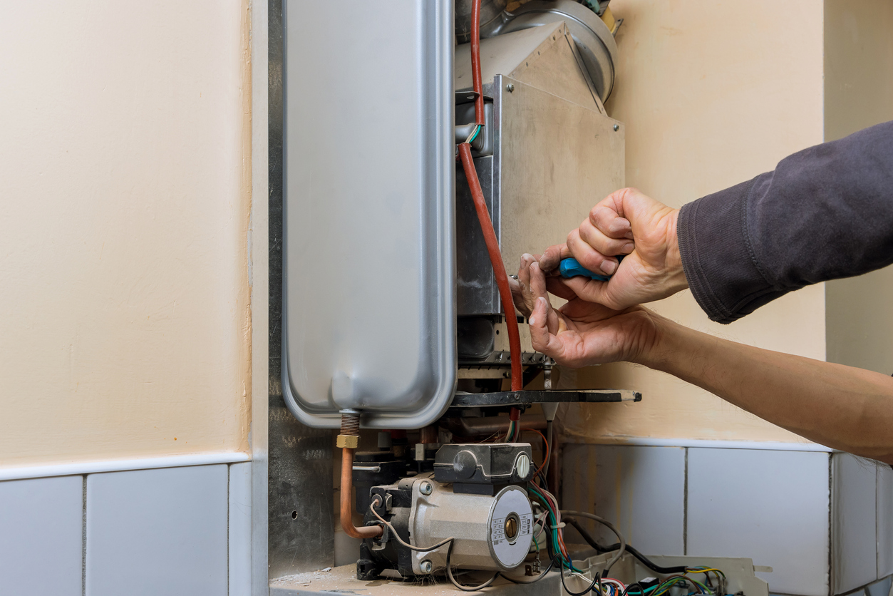 Repairman fixing a gas water heater with repair service Repairman fixing a gas water heater with repair service