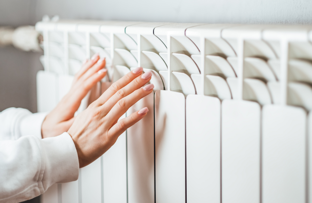Woman warms up hands over heater. Woman warms up hands over heater.