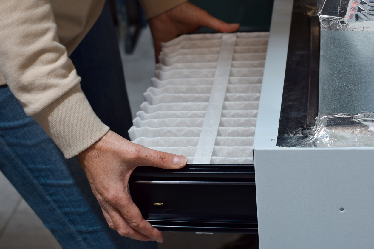 Woman is replacing furnace filter at home Woman is replacing furnace filter at home